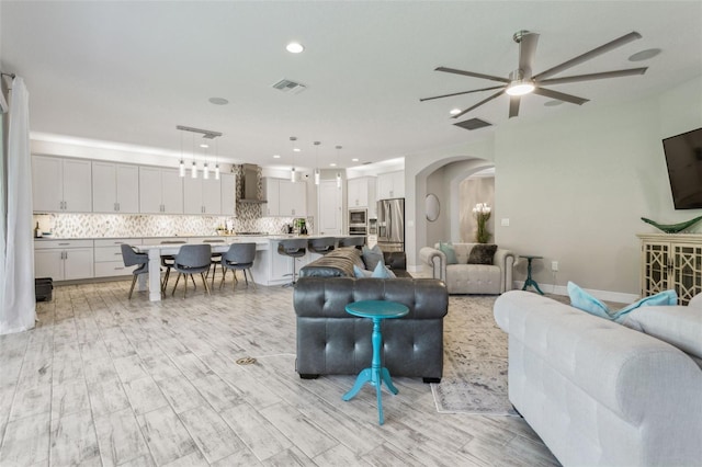 living room with ceiling fan and light wood-type flooring