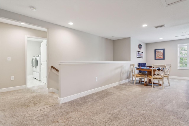 dining area with separate washer and dryer and light colored carpet