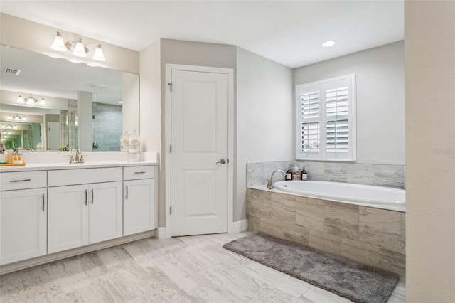 bathroom with vanity and tiled tub