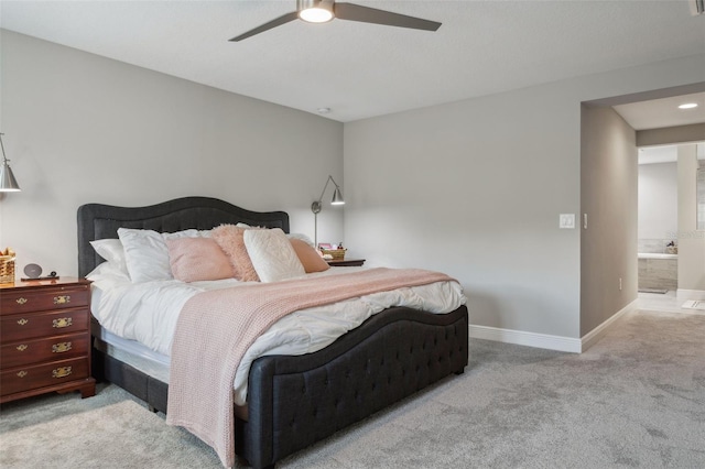 bedroom with ceiling fan, ensuite bathroom, and light colored carpet