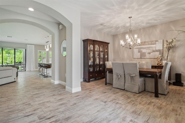 dining room featuring arched walkways, recessed lighting, wood finished floors, baseboards, and an inviting chandelier