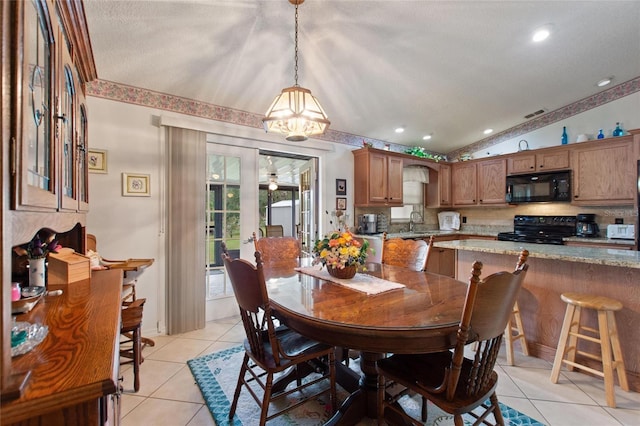 dining room featuring lofted ceiling, light tile patterned floors, sink, and a textured ceiling