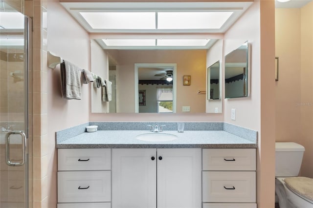 bathroom with walk in shower, ceiling fan, vanity, and toilet