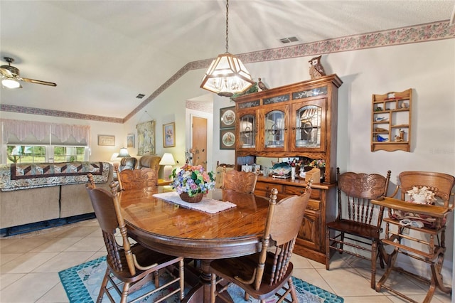 tiled dining space featuring lofted ceiling and ceiling fan with notable chandelier