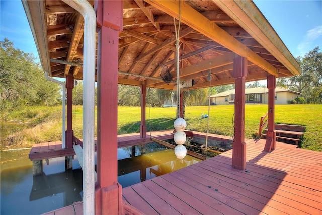 view of dock with a yard and a water view