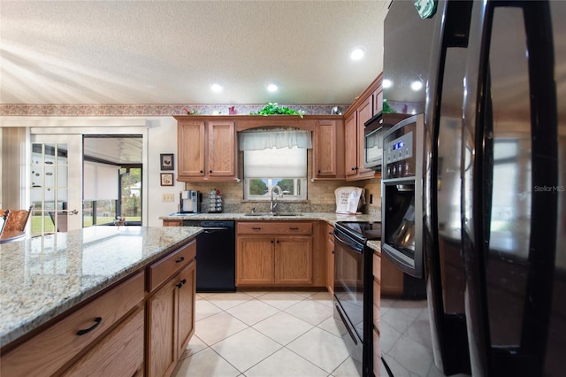 kitchen with sink, light tile patterned floors, black appliances, light stone countertops, and a textured ceiling