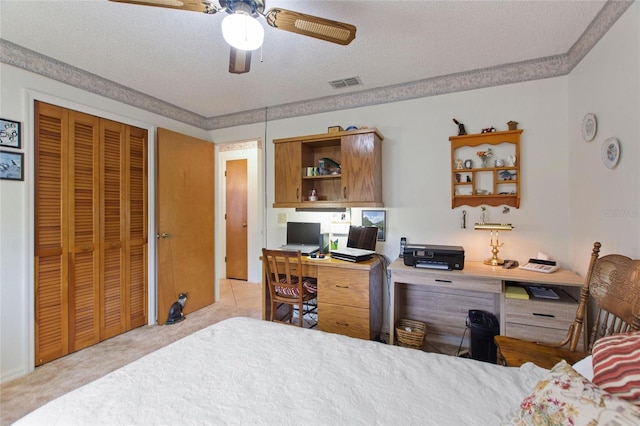 bedroom with light carpet, ceiling fan, a closet, and a textured ceiling