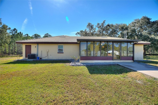 rear view of house featuring a sunroom, central AC unit, and a lawn