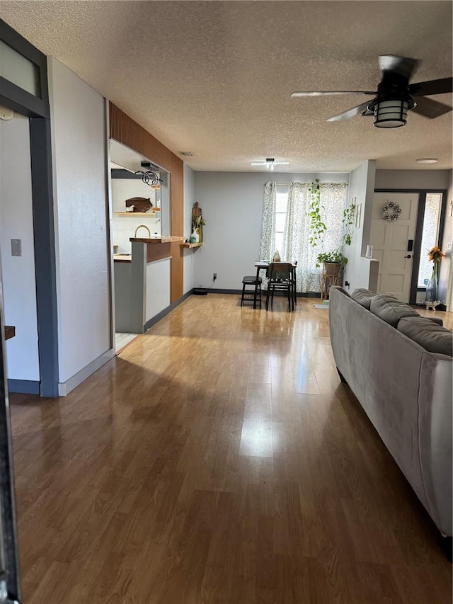 unfurnished living room with ceiling fan, a textured ceiling, and hardwood / wood-style floors