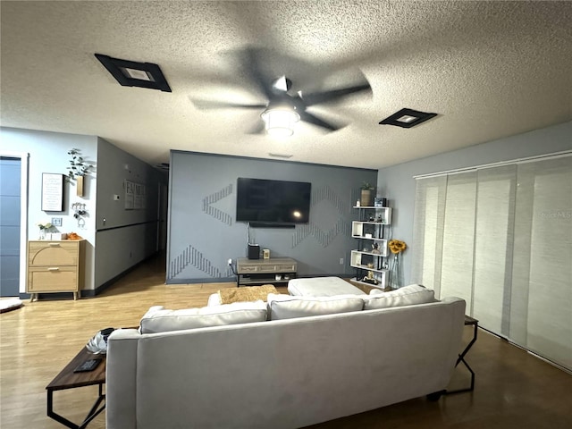 living room featuring ceiling fan, a textured ceiling, and wood-type flooring