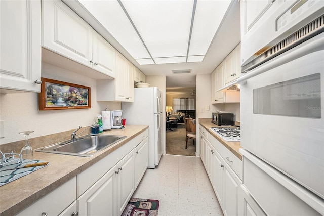 kitchen with sink, white appliances, and white cabinets