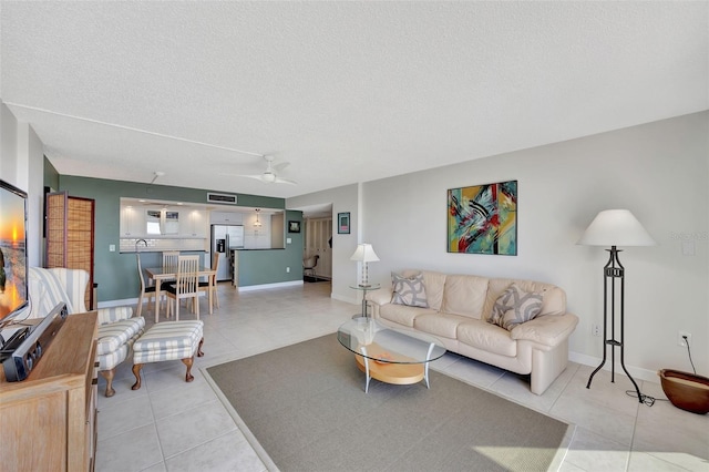 tiled living room with ceiling fan and a textured ceiling