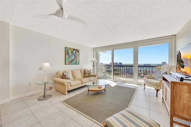 living room featuring a textured ceiling, expansive windows, ceiling fan, and light tile patterned flooring