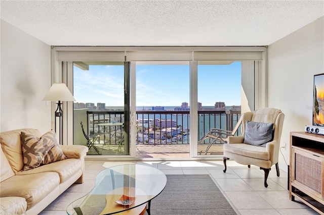 living room with expansive windows, a water view, and a healthy amount of sunlight