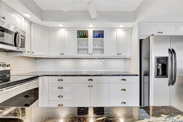 kitchen featuring dark stone countertops, tasteful backsplash, white cabinets, and appliances with stainless steel finishes