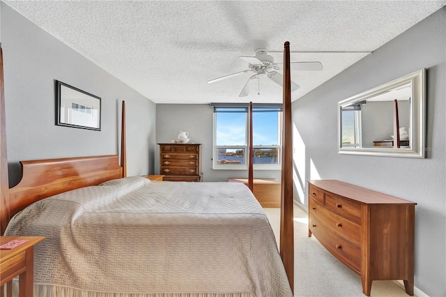 bedroom featuring ceiling fan, light colored carpet, and a textured ceiling