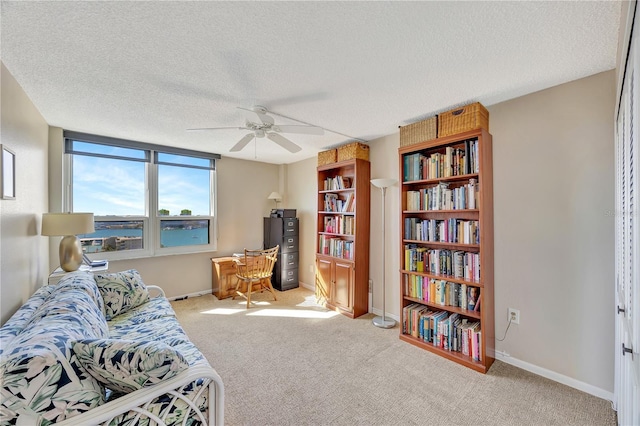 sitting room with ceiling fan, light colored carpet, and a textured ceiling