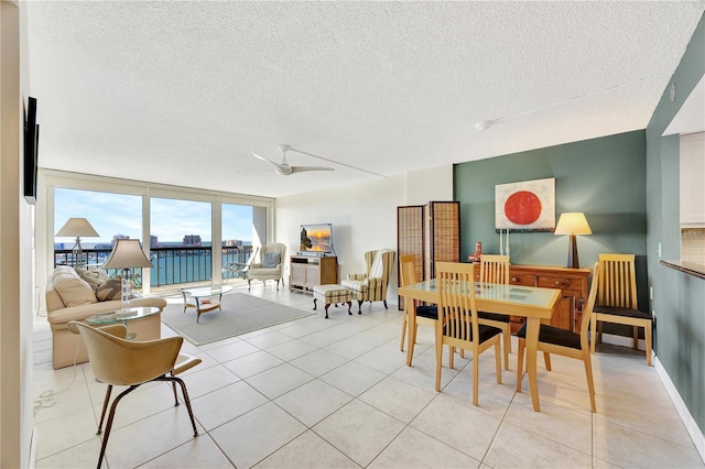 dining room featuring a textured ceiling, a wall of windows, ceiling fan, and light tile patterned flooring