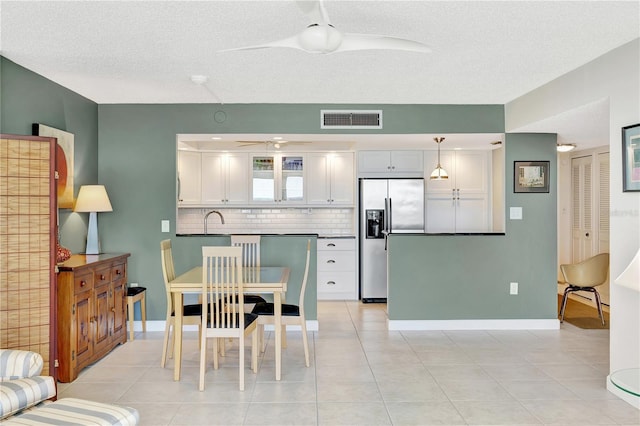 kitchen featuring ceiling fan, stainless steel refrigerator with ice dispenser, decorative backsplash, white cabinets, and decorative light fixtures