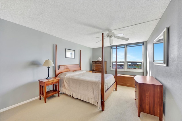 carpeted bedroom featuring ceiling fan and a textured ceiling