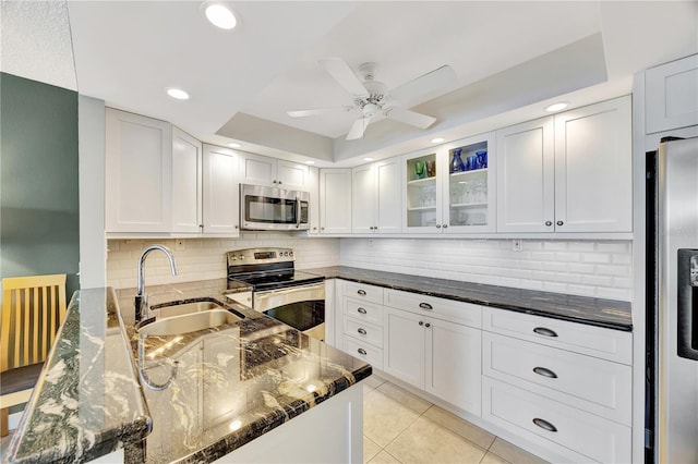 kitchen featuring sink, white cabinetry, dark stone countertops, a raised ceiling, and stainless steel appliances