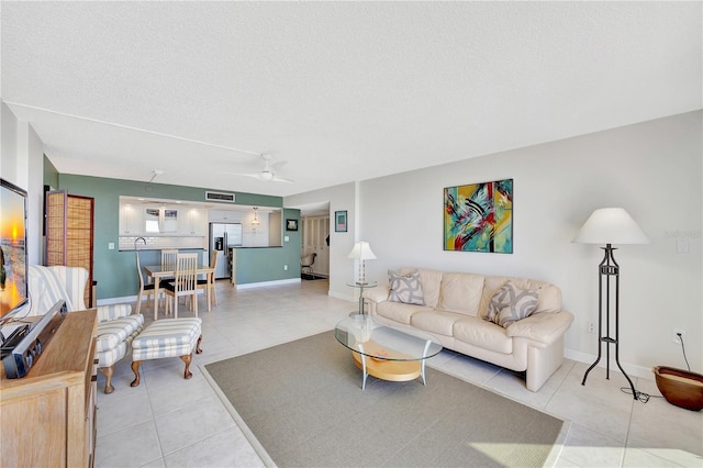 living room featuring ceiling fan, a textured ceiling, and light tile patterned floors