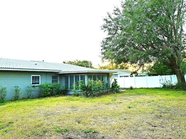 back of property featuring a sunroom and a lawn