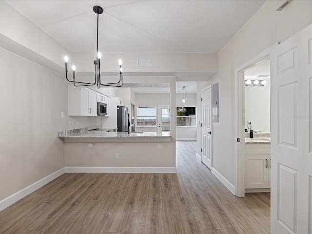 kitchen with pendant lighting, white cabinetry, kitchen peninsula, stainless steel appliances, and light hardwood / wood-style flooring