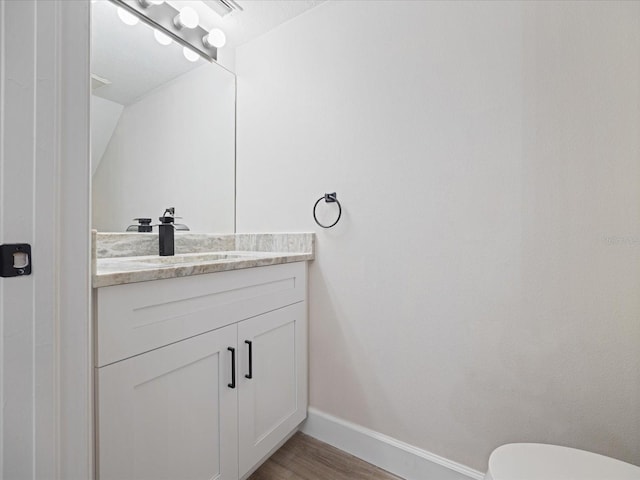 bathroom with hardwood / wood-style flooring, vanity, lofted ceiling, and toilet