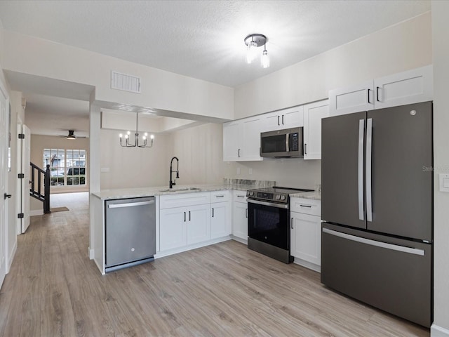 kitchen featuring sink, decorative light fixtures, white cabinets, and appliances with stainless steel finishes