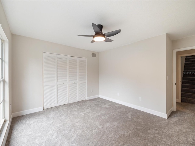 unfurnished bedroom featuring light colored carpet, a closet, and ceiling fan