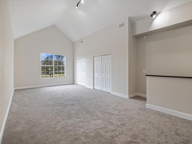 empty room featuring light colored carpet and high vaulted ceiling