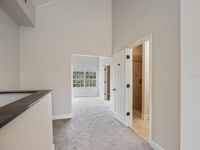 hall featuring light carpet and a high ceiling