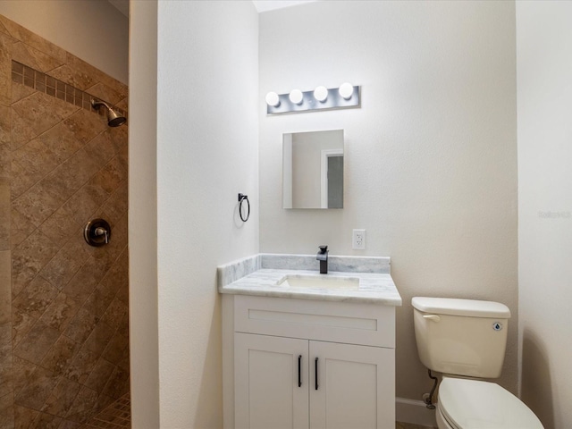 bathroom with tiled shower, vanity, and toilet