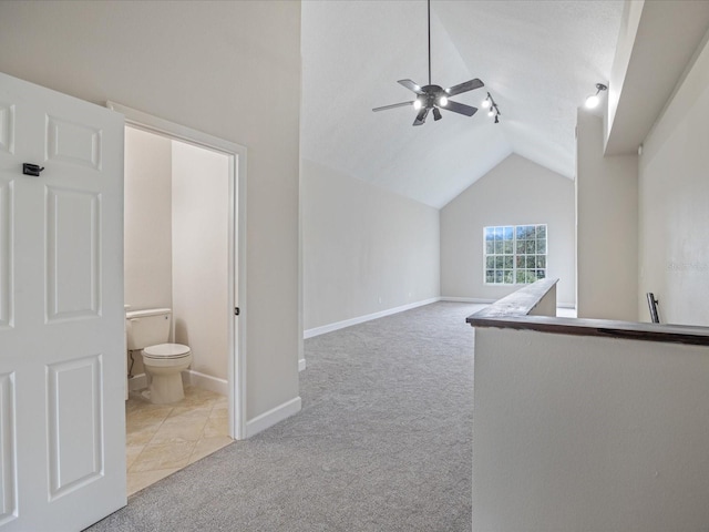 interior space featuring ceiling fan, light colored carpet, and lofted ceiling