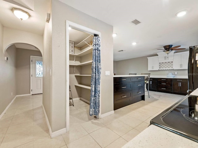 kitchen with dark brown cabinets, black refrigerator, ceiling fan, white cabinetry, and light tile patterned floors