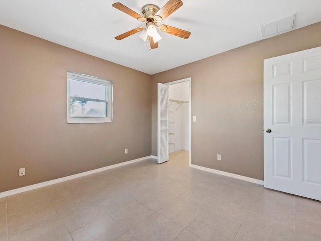 interior space with light tile patterned floors, a closet, a spacious closet, and ceiling fan