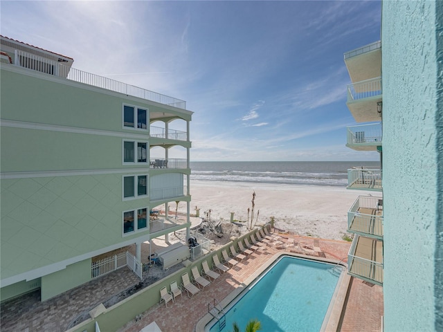 view of pool with a water view, a view of the beach, and a patio area