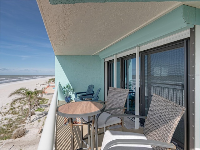 balcony with a water view and a view of the beach