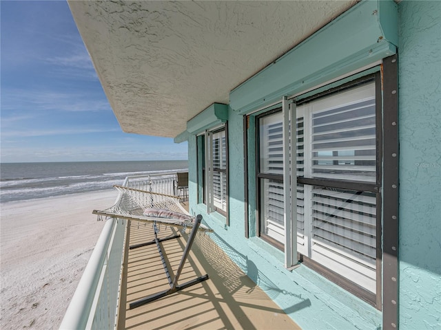 balcony featuring a water view and a beach view