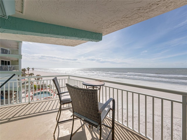 balcony featuring a water view and a beach view