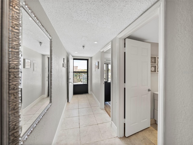 corridor featuring light tile patterned floors and a textured ceiling