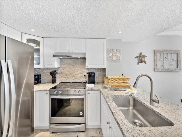 kitchen with a textured ceiling, white cabinets, stainless steel appliances, sink, and light tile patterned floors