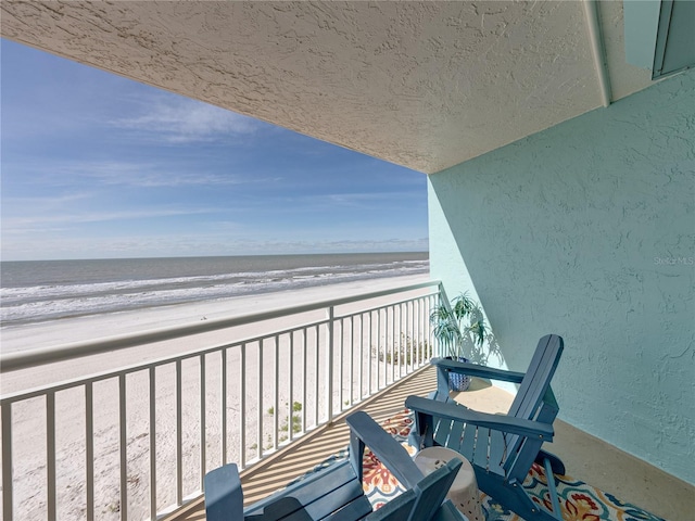 balcony featuring a water view and a beach view