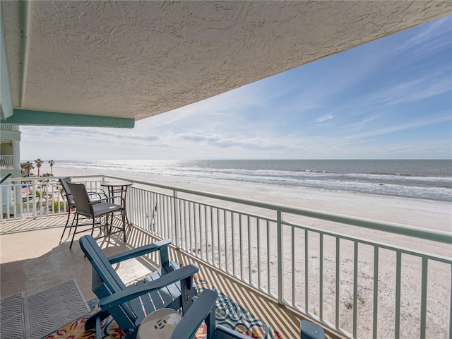 balcony with a water view and a view of the beach