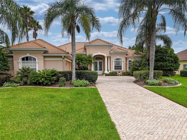 mediterranean / spanish home with a front lawn and french doors