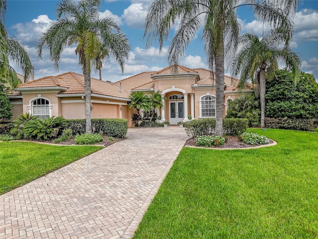 mediterranean / spanish house featuring a garage, a front yard, and french doors