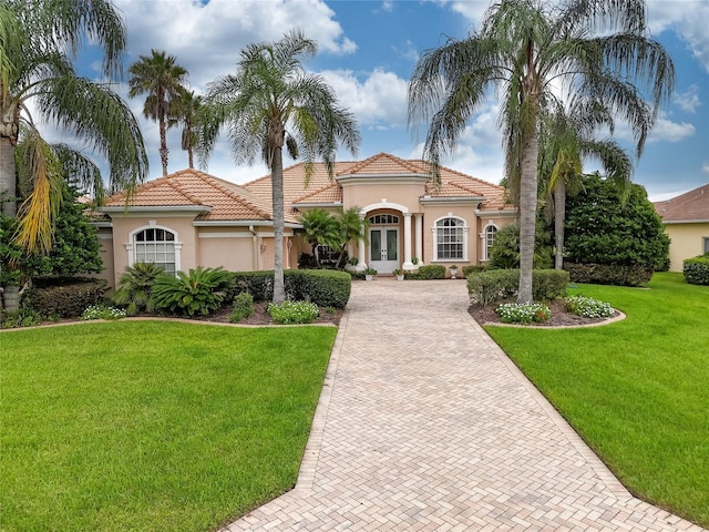 mediterranean / spanish-style house with a garage, a front yard, and french doors