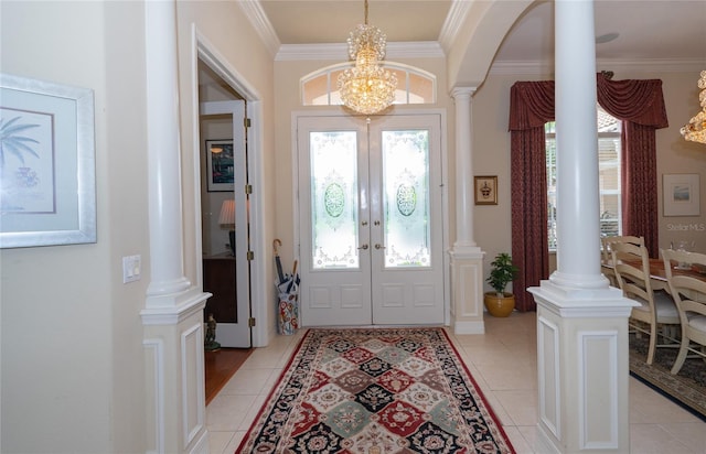 foyer entrance with ornamental molding, ornate columns, and light tile patterned flooring