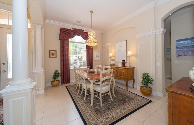 tiled dining room featuring decorative columns, ornamental molding, and an inviting chandelier